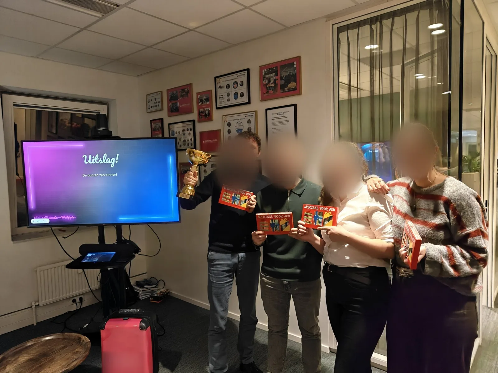 Winnaars van de pubquiz met een trofee voor het scherm met de uitslag